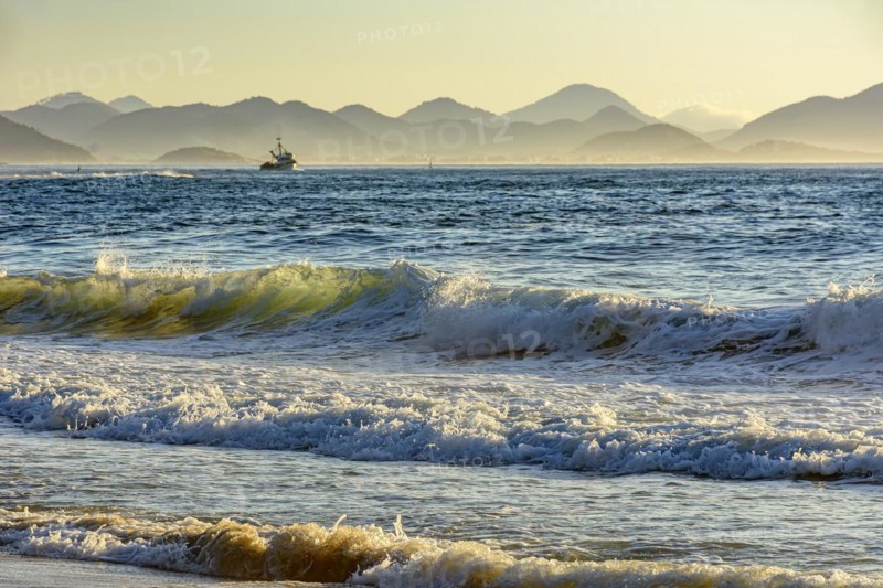 Sunrise on Devil beach in Ipanema in Rio de Janeiro with a fishing boat and mountains in the background.