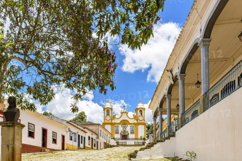 A quiet historic cobblestone street in the city of Tiradentes in Minas Gerais with colonial houses and a baroque church in the background