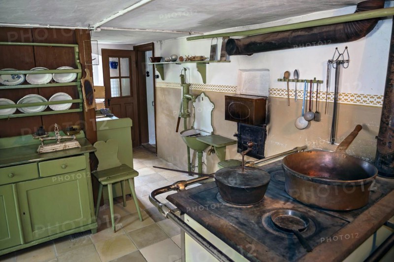 Kitchen with old wood or coal cooker and hand-operated swing pump