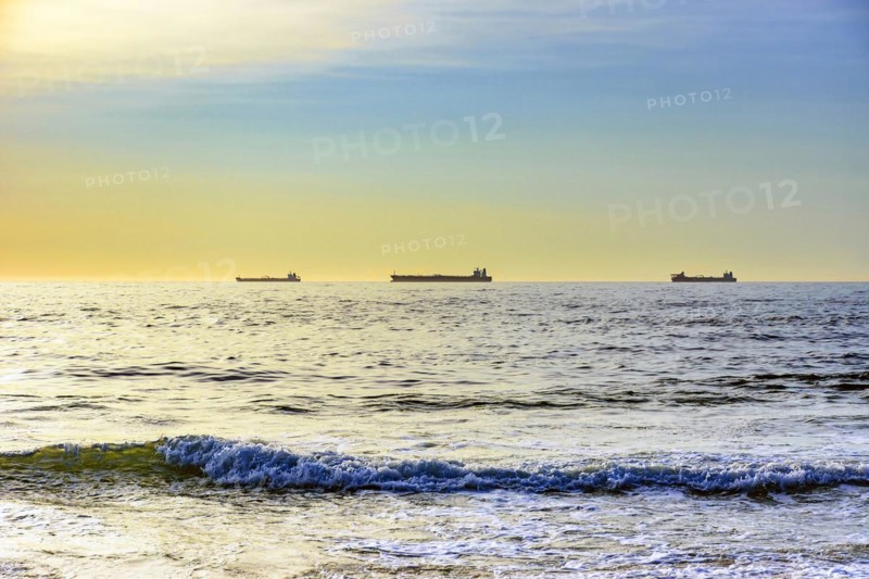 Ships moored on the horizon waiting to go to port during dawn on Ipanema beach in Rio de Janeiro