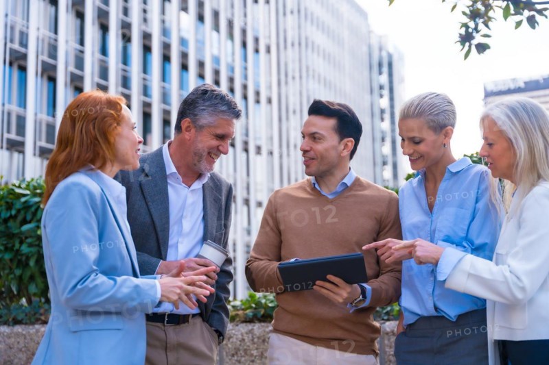 Chatting and seeing work stuff on a tablet. Group executives or businessmen and businesswoman in a business area