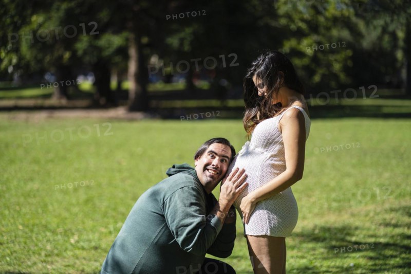 Man listening to his pregnant wife's tummy and smiling