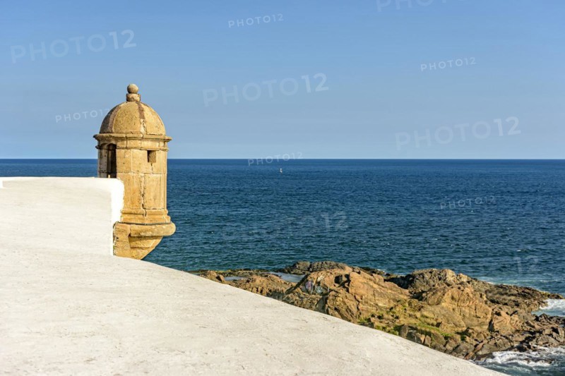 Walls and guardhouse of old fortification with the sea and stones in the background in the city of Salvador in Bahia