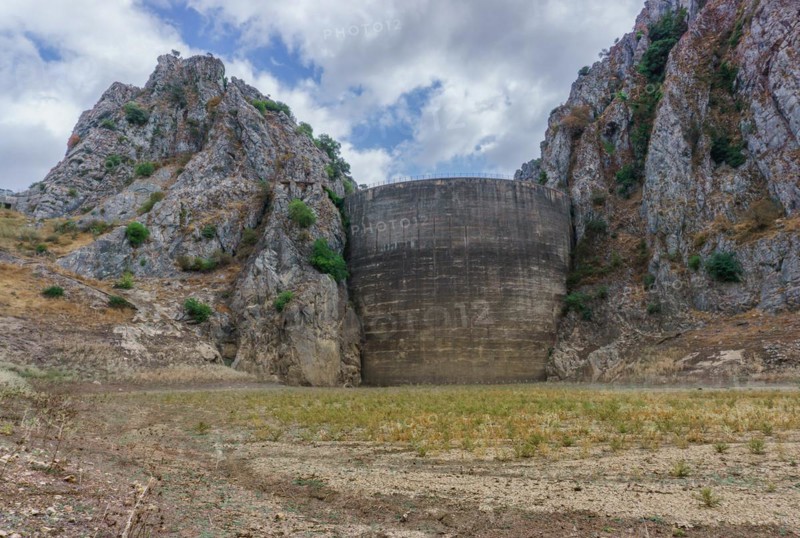 This striking photograph depicts a reservoir dam during a severe drought. The reservoir