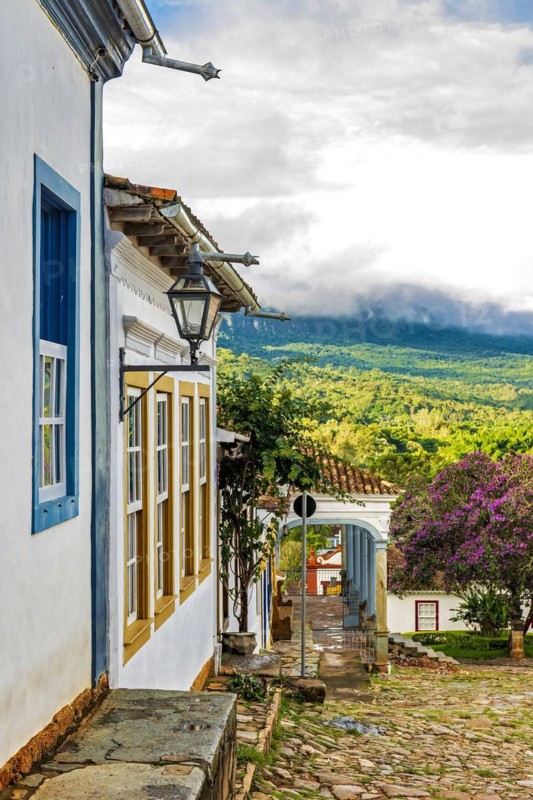 Facade of old colorful colonial houses in the historic city of Tiradentes with the forest and mountains in the background