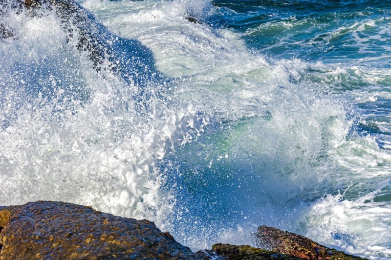 Wave crashing against the rocks with sea water splashing in the air