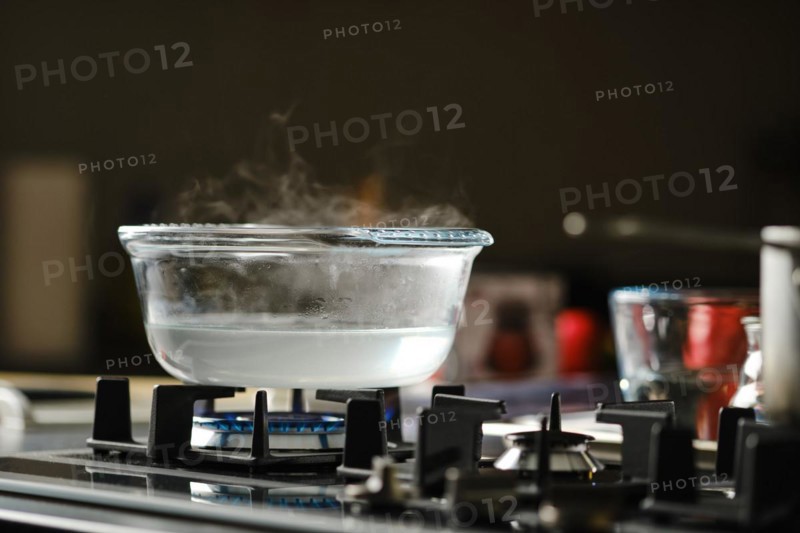Process of boiling water in transparent casserole on gas stove