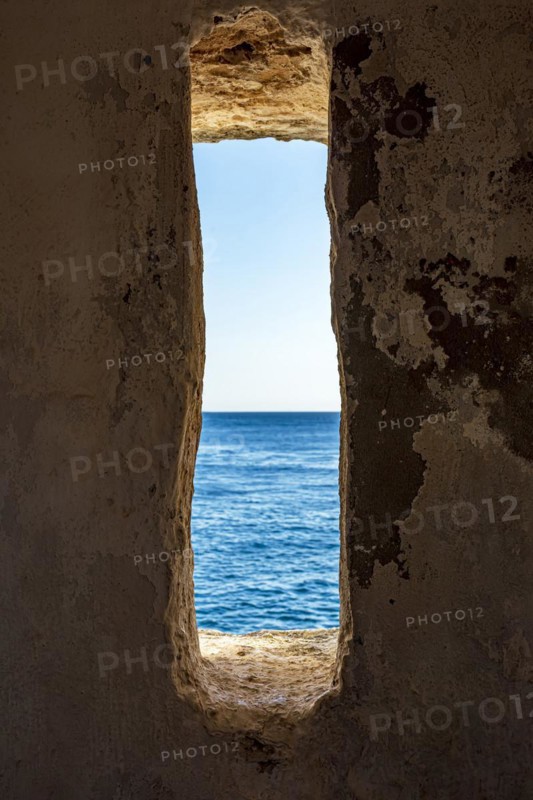 A window to the sea. View of the sea and horizon in the guardhouse of an old fortress from the 17th century in the city of Salvador