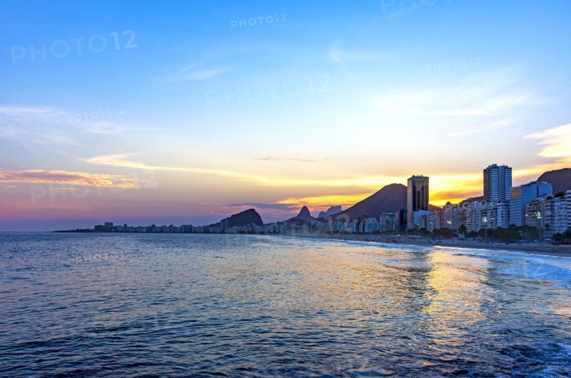 Copacabana beach sunset in Rio de Janeiro with the light coming from behind the buildings and hills