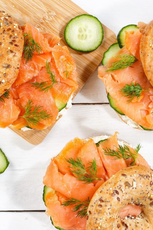 Bagel sandwich for breakfast topped with salmon fish from above on a wooden board in Stuttgart