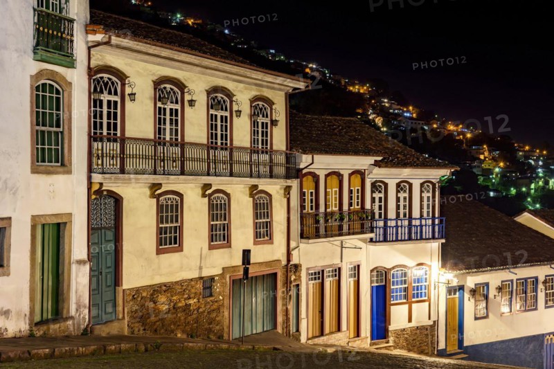 Facades of houses in colonial architecture on an old cobblestone street in the city of Ouro Preto illuminated at night