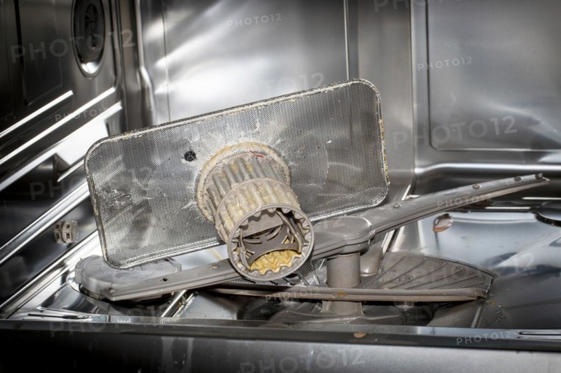A heavily soiled drain strainer in a dishwasher