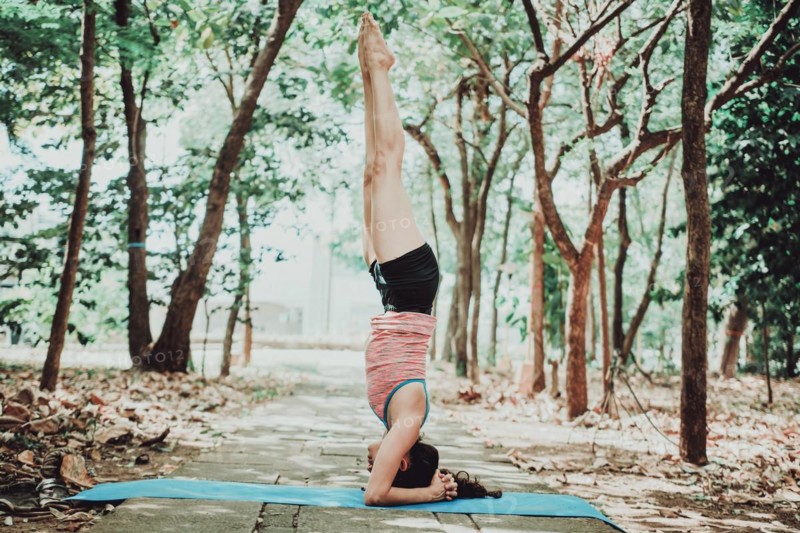 Young woman doing headstand yoga outdoors. Spiritual girl practicing yoga sirshasana outdoors