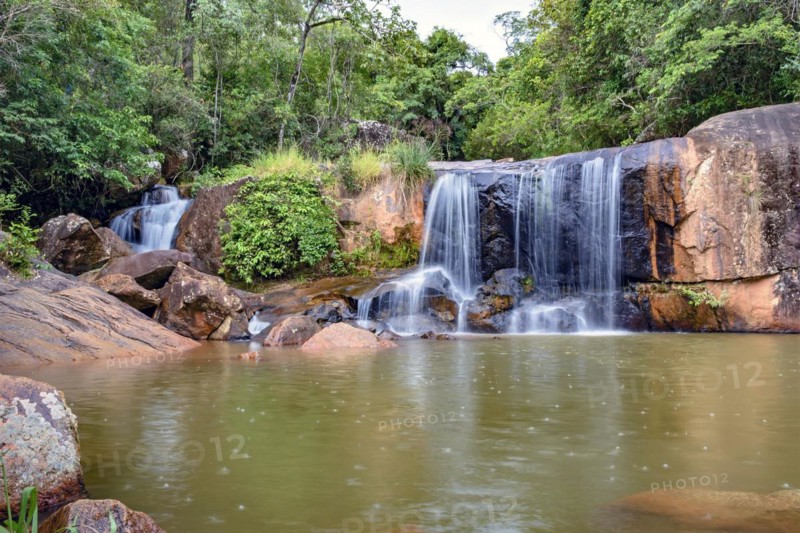 Waterfall and lake in rain forest of Moeda in Minas Gerais state on cloudy day among rocks and vegetation