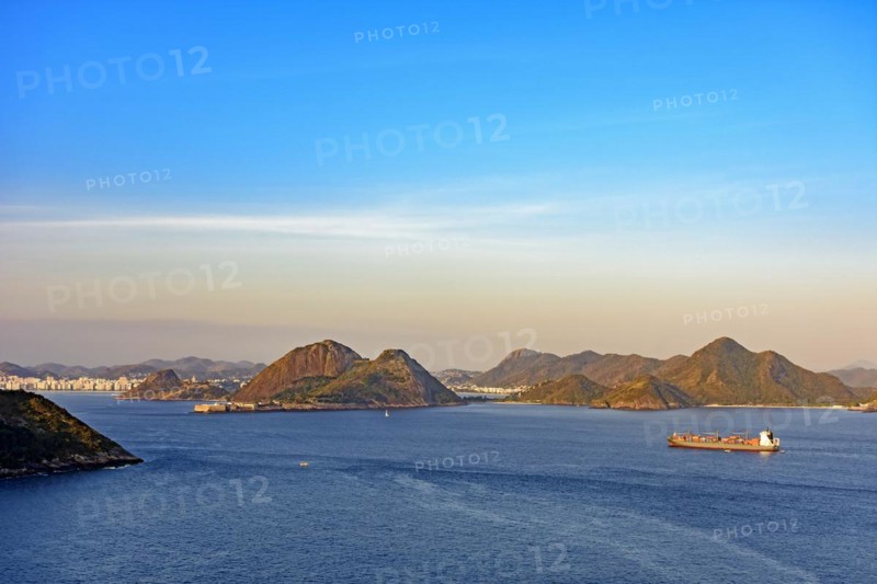 Cargo ship arriving at the entrance of the Guanabara Bay in Rio de Janeiro with Niteroi city in background at afternoon