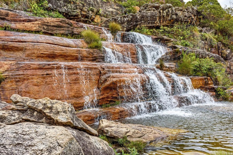 Small waterfall with clear water running over the rocks and ending in a small lake in the Biribiri environmental reserve in Diamantina