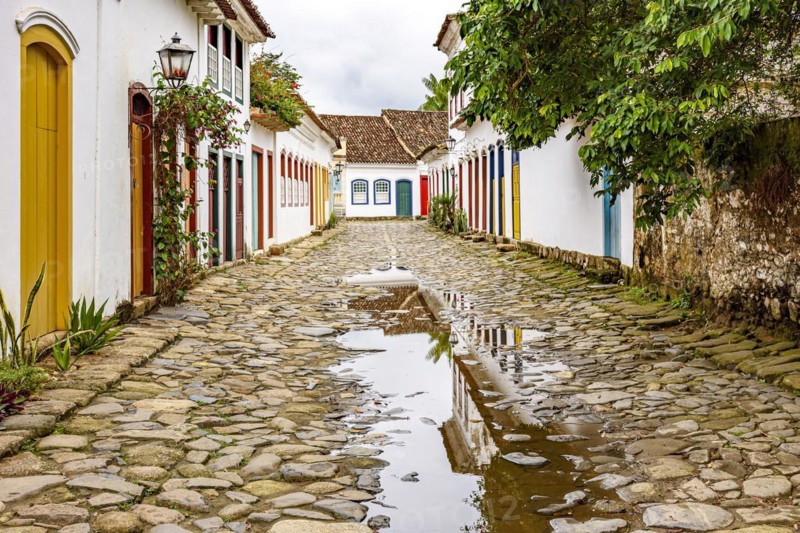 Cobblestone street with colorful colonial houses and reflections in the puddles in the historic city of Paraty