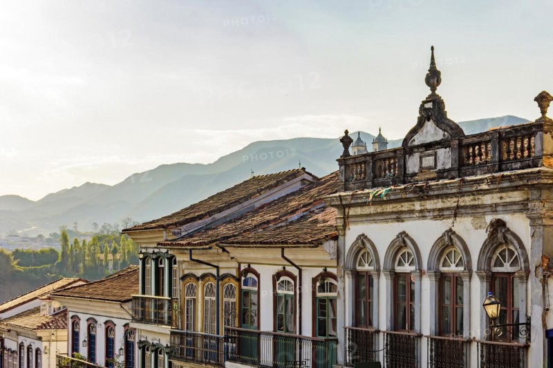 Facades of houses in colonial architecture in an old street in the city of Ouro Preto with the mountains in the background
