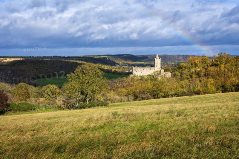 Rudelsburg castle ruins in the Saale valley in autumn under dark clouds and rainbow