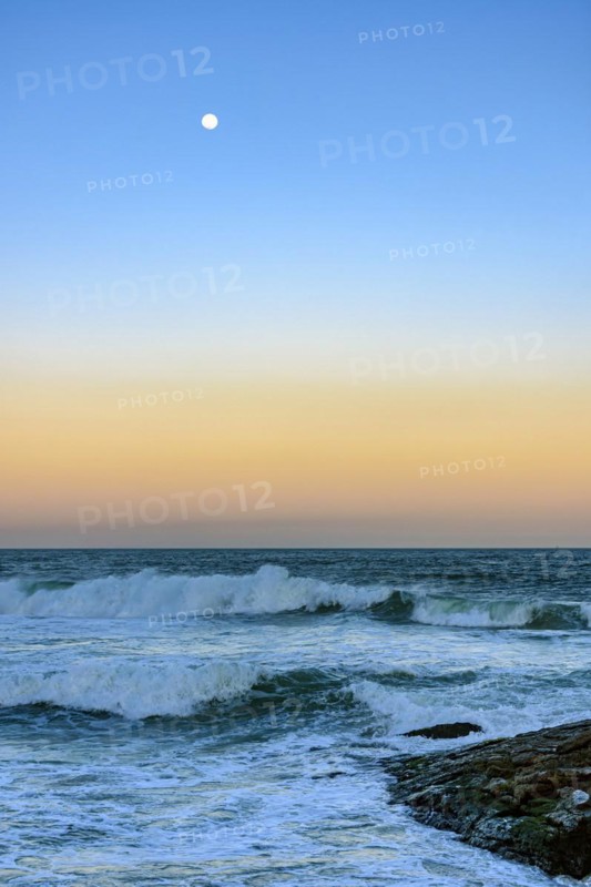 Moon over the sea and waves during sunset at Ipanema beach in Rio de Janeiro