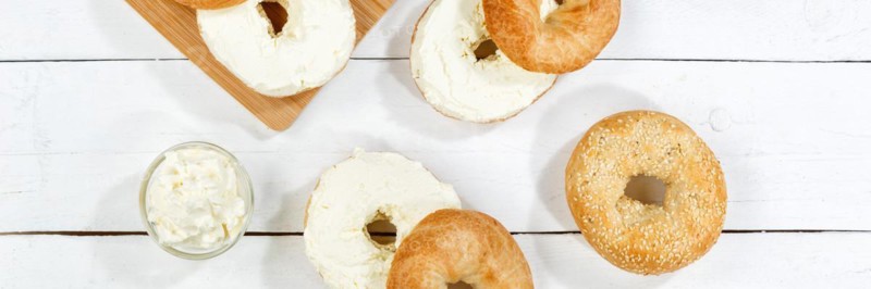 Bagel sandwich for breakfast topped with cream cheese on wooden board from above Panorama in Stuttgart