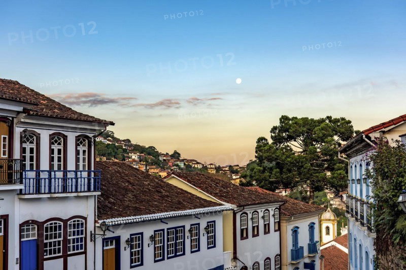 Old colonial style houses with their balconies in the traditional historic town of Ouro Preto during sunset with the moon in the background