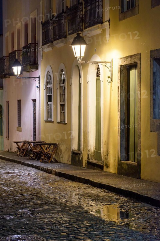Old cobblestone street with lantern-lit colonial houses at night in the Pelourinho neighborhood of Salvador
