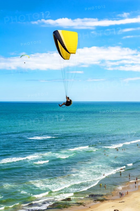 Paraglider flight over the beach in the city of Torres in Rio Grande do Sul with the sea and horizon in the background