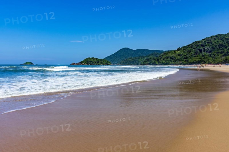 Paradise beach surrounded by rainforest and hills on a sunny day in Bertioga on the coast of Sao Paulo