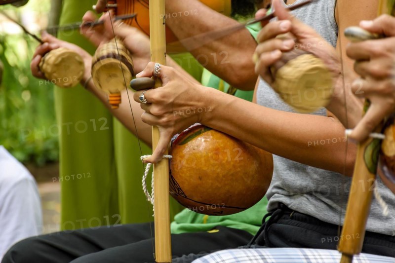 Several musicians playing an Afro Brazilian percussion musical instrument called the berimbau during a capoeira performance in the streets of Brazil