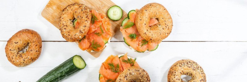 Bagel sandwich for breakfast topped with salmon fish from above on a wooden board Panorama in Stuttgart