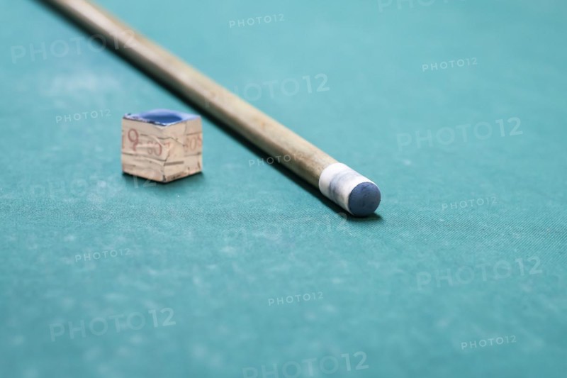 A cue stick and a chalk on a pool table