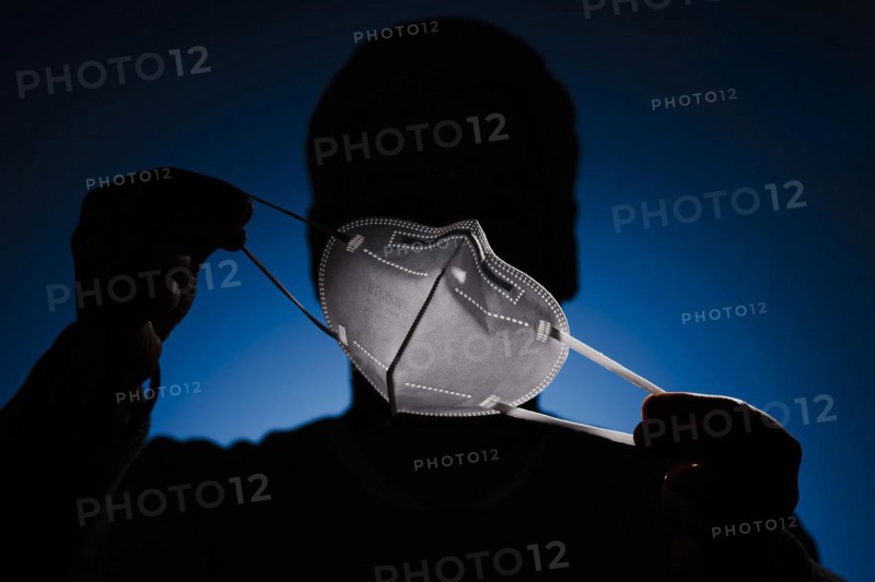 A man holds an FFP2 protective mask in front of his face. Berlin