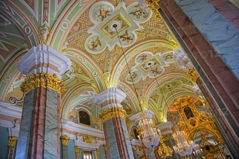 Luxurious crystal chandeliers and vaults with ceiling paintings portraying angels inside the Peter and Paul Cathedral in Saint Petersburg