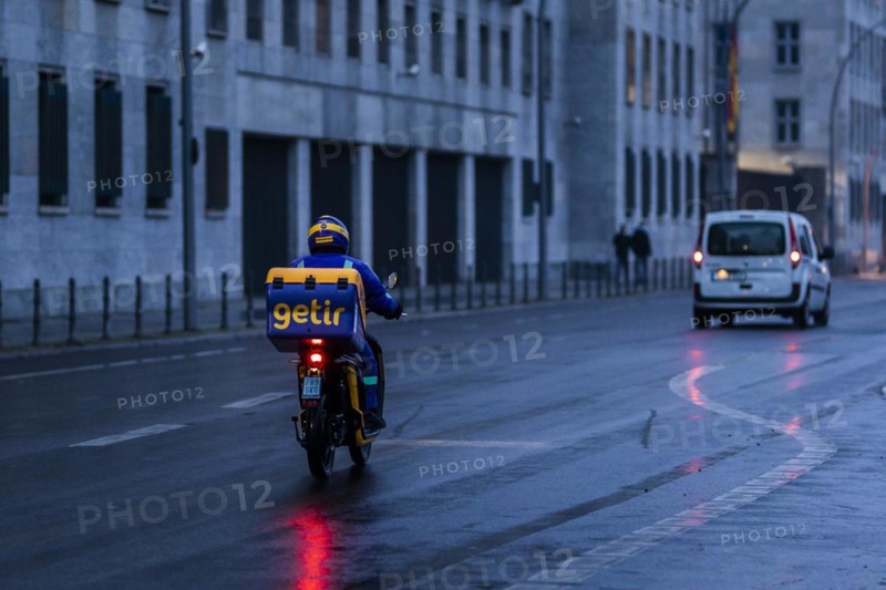 An employee of the delivery service Getir drives along Wilhemstrasse in the evening in Berlin