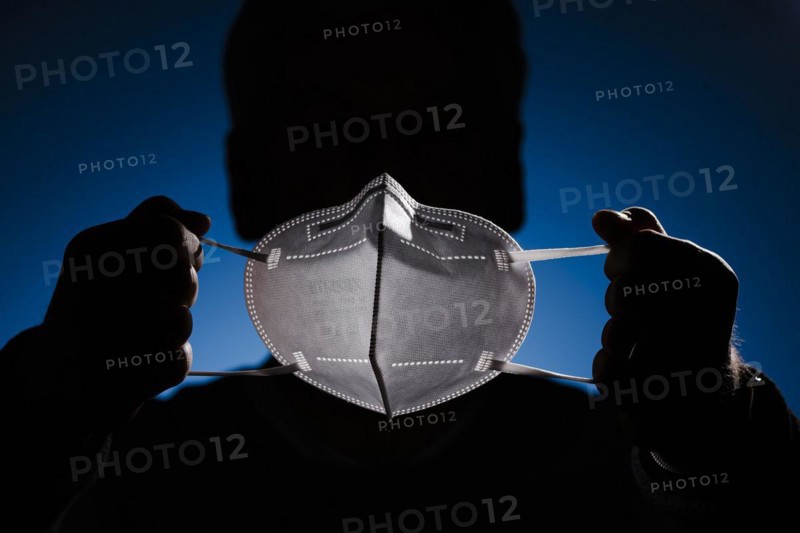 A man holds an FFP2 protective mask in front of his face. Berlin