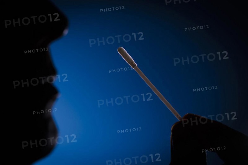 A man holds cotton swabs of a Sars-COV-2 Rapid Antigen Test to his nose. Berlin