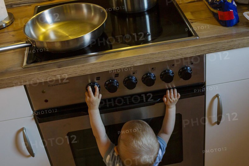 Symbol photo on the topic of dangers for small children in the household. A small child plays with the knobs of a cooker. Berlin