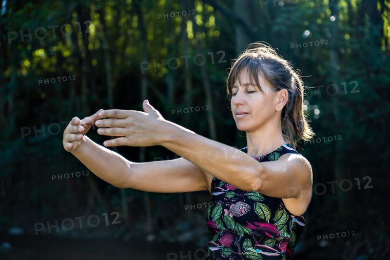 Qigong Female Master Practicing Chinese Martial Arts in Nature. Sunlight illuminates the scene