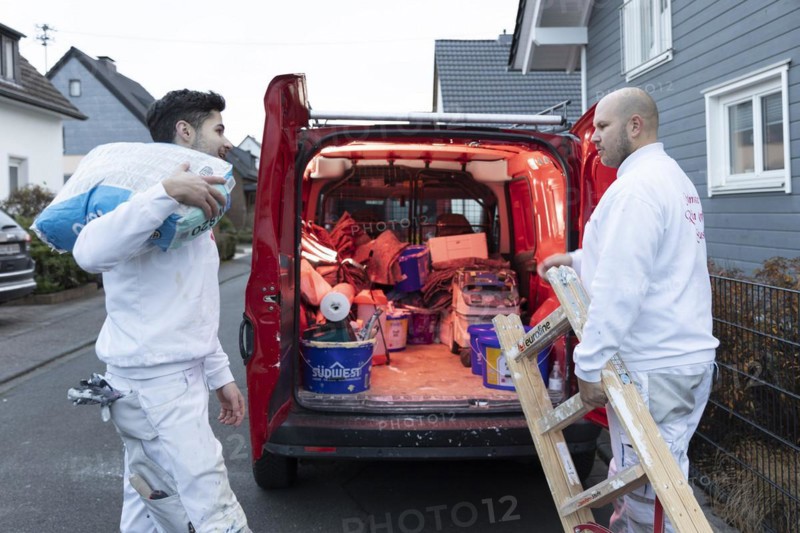 Subject: Master painter and apprentice loading a van with work materials