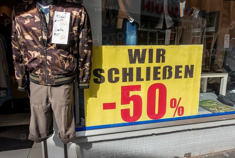 Sign with 50 percent discount due to business closure at the window of a clothing shop in the pedestrian zone