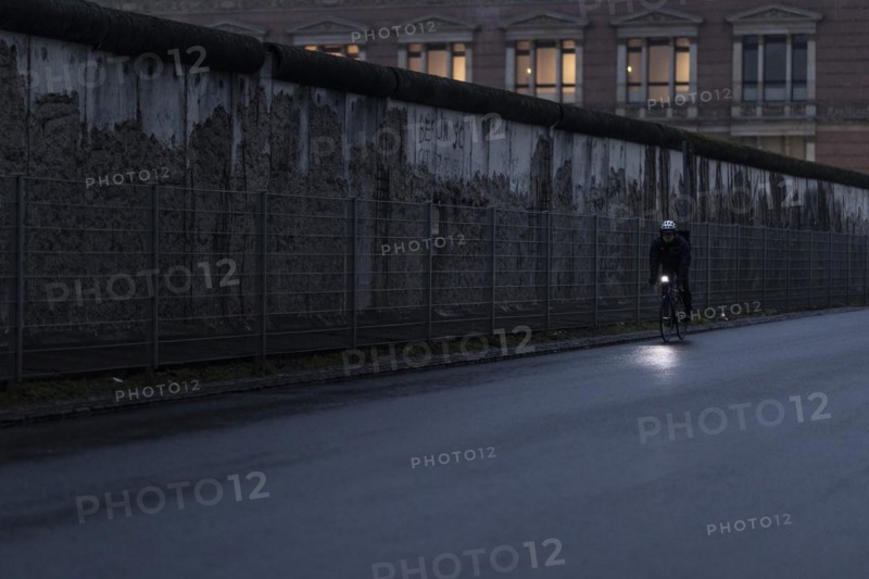 A cyclist stands out in front of the Berlin Wall in Berlin