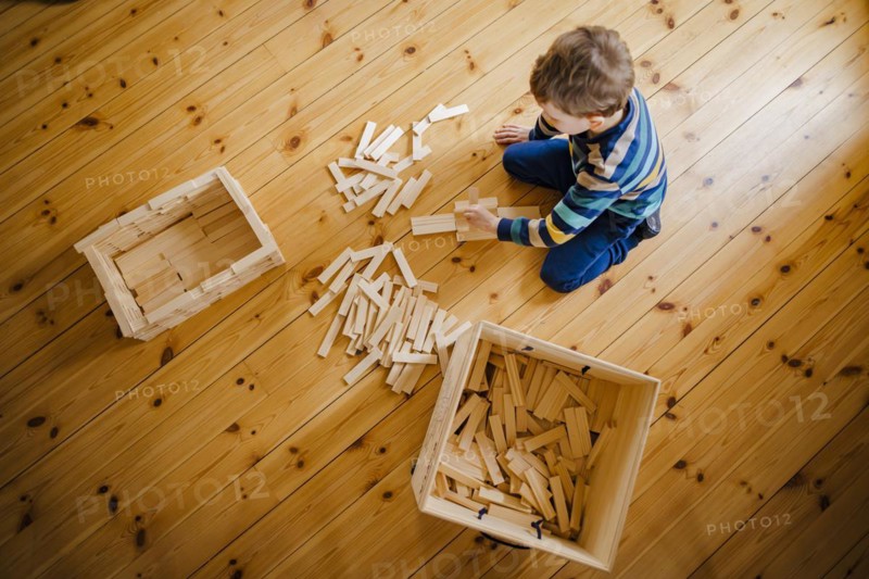 Symbolic photo on the subject of creative play among children. A boy builds with wooden building blocks. Berlin