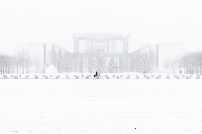 A person is silhouetted in front of the Chancellery in the driving snow in Berlin