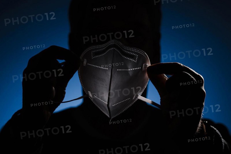 A man holds an FFP2 protective mask in front of his face. Berlin