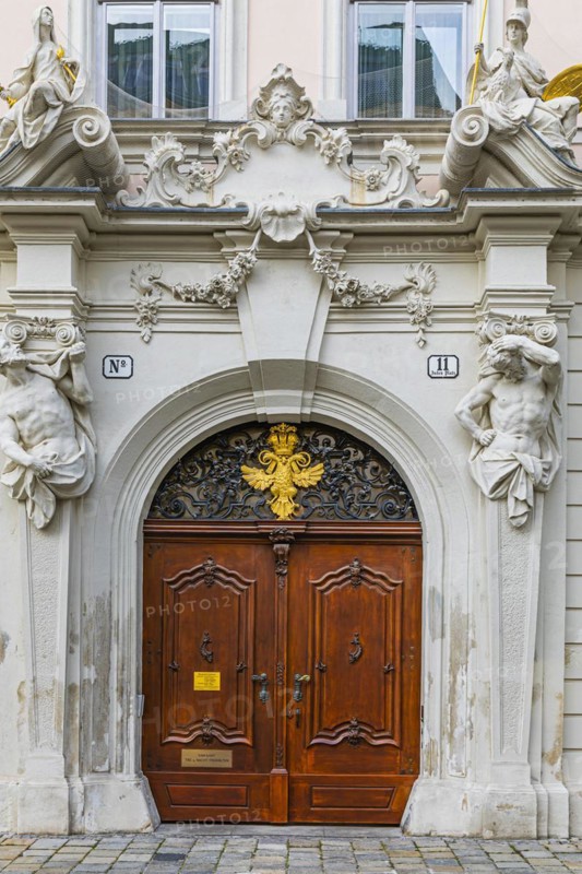 Round arched front door framed with stone figures