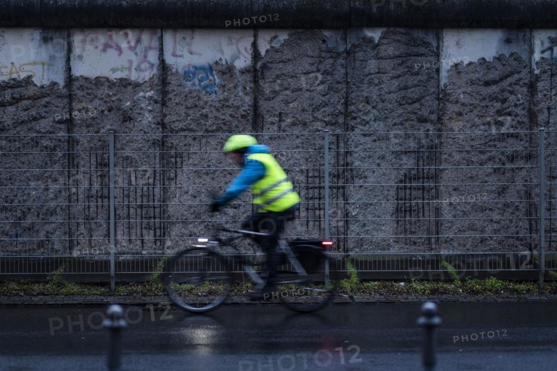 A cyclist stands out in front of the Berlin Wall in Berlin