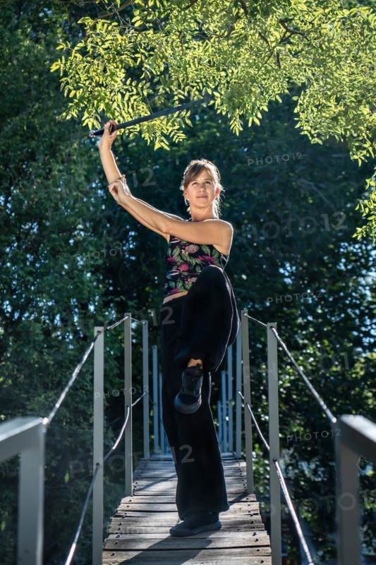 Woman practices tai chi sword on a bridge. The tai chi sword is an important instrument in this practice