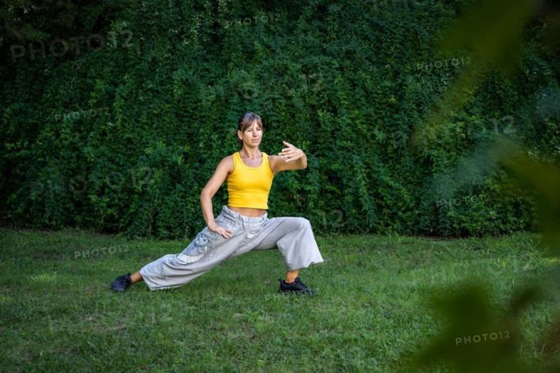 A woman practices Tai Chi in a park. Practicing outdoors provides a calm and relaxing environment for meditation and concentration