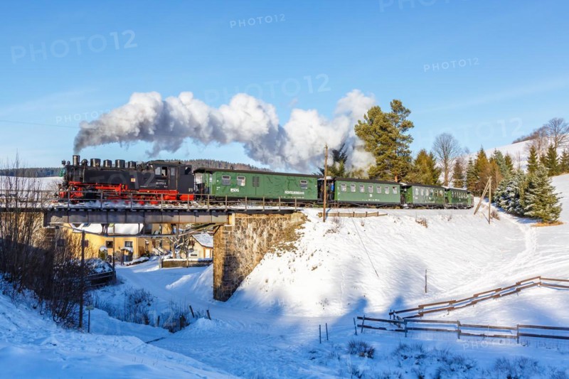 Steam train of the Fichtelbergbahn railway Steam locomotive on a bridge in winter in Sehmatal